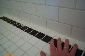 hand touching faulty shower tiling