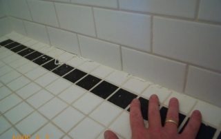 hand touching faulty shower tiling